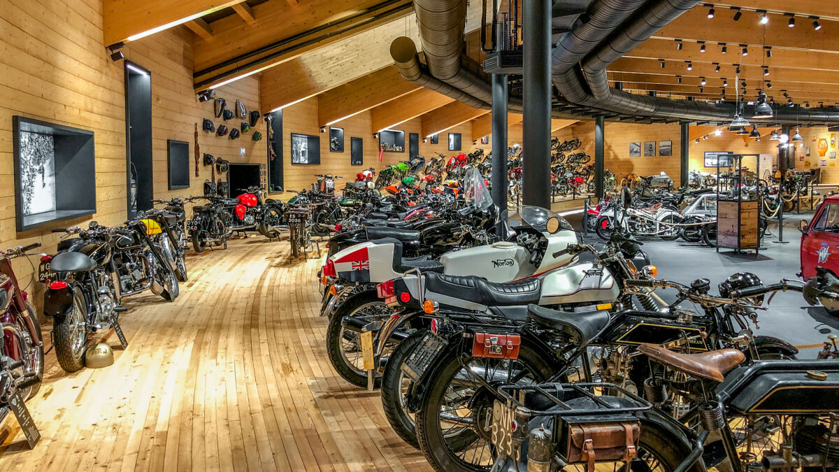Halle aus hellem Holz mit Dutzenden historischen Motorrädern in Reihen, vorn eine Norton